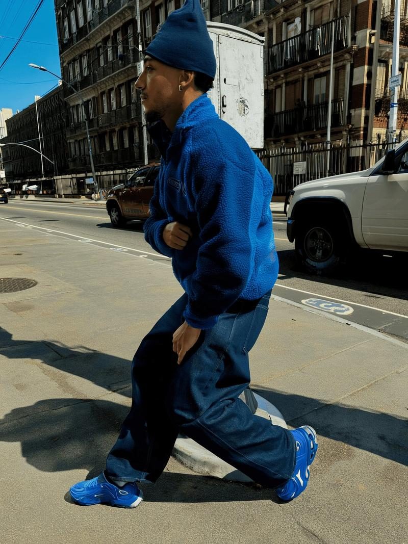 Chico con chaqueta azul y gorro en una calle soleada, imagen de lookbook